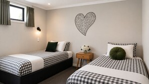 Ein Schlafzimmer mit zwei Betten, einem Nachttisch, einer Wandleuchte und einer herzförmigen Dekoration.