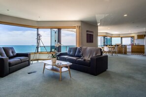 A spacious living area with a view of the sea, a dining area, and a kitchen. - Waterfront On Woolcombe - Spacious Holiday Home (New Plymouth)