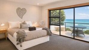 Ein Schlafzimmer mit einem großen Bett, einer Wanddekoration in Herzform, einem Balkon mit Meerblick und einem Tisch mit Stühlen.