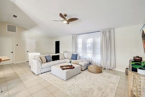 A spacious living room with a white sofa, a coffee table, and a ceiling fan. - Western Sunsets-Heated Pool-Dock-Fresh Water Canal (Cape Coral)