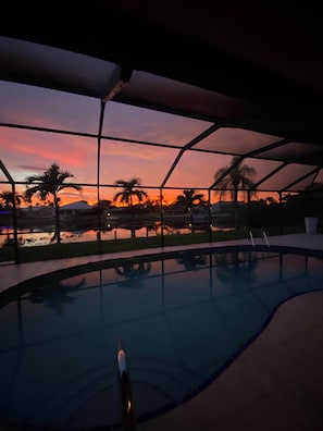 Une piscine avec vue sur les palmiers et sur le coucher de soleil.