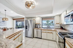 Una cocina moderna con una isla central, electrodomésticos de acero inoxidable y vistas al exterior.