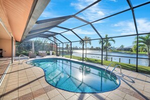 Une piscine avec vue sur un plan d’eau et des palmiers.