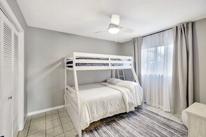 A bunk bed room with a ceiling fan, a window with curtains, and a tiled floor. - Western Sunsets-Heated Pool-Dock-Fresh Water Canal (Cape Coral)