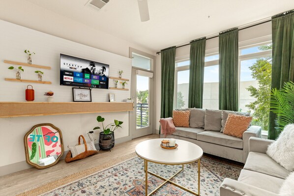 A modern living room with a sofa, coffee table, and TV mounted on the wall. - Riverwalk Suite, Walkable to the Alamo, Pearl and Downtown, Infinity Pool, Park (San Antonio)