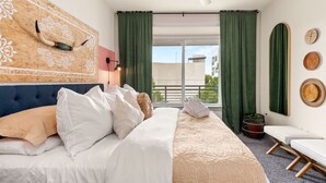 Habitación de hotel con cama, ventilador de techo, vistas al exterior y cortinas.