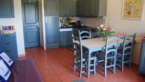 A kitchen with grey cabinets, a stainless steel refrigerator, a dining table with four chairs, and a tiled floor. - Cornazur: Ocean View, Pool, and Reversible Air Conditioning (ROQUEBRUNE SUR ARGENS)
