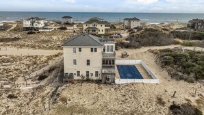 A beachfront property with a large house, a tennis court, and multiple smaller houses in the background. - SALTED SHORES OBX formerlyPLAYING HOOKY, 5bed,Wild Horses,Pool,Hot Tub,4x4 Beach (Corolla)
