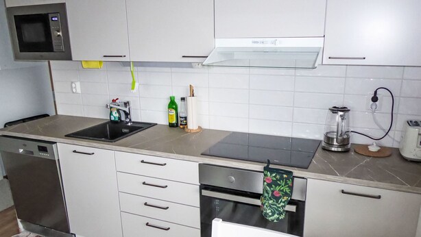 Una cocina moderna con microondas, fregadero, estufa y tetera.