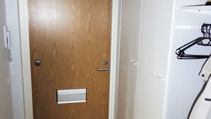 Una puerta de madera con un buzón, una pared blanca y un perchero con colgadores.