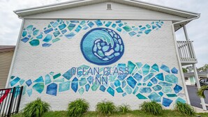 Un edificio con un mural de mosaico que presenta un diseño circular y las palabras 'OCEAN GLASS INN'.