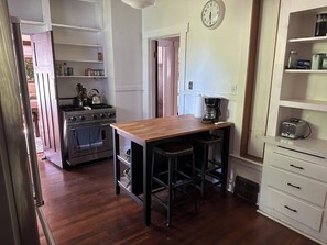 Una cocina con una mesa de madera, una cafetera, un tostador y una estufa.
