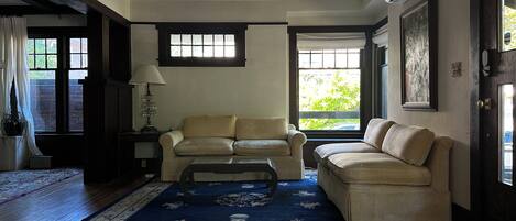 A living room with two sofas, a chandelier, and a large window with curtains.