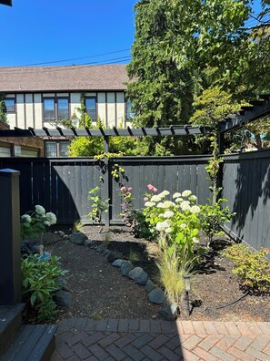 A garden with a wooden fence, various plants, and a brick pathway. - Charming 2 bed Craftsman in Upper Fremont, close to everything w/ private garden (Seattle)