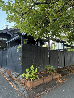 A residential property with a wooden fence, a covered porch, and a garden area with plants. - Charming 2 bed Craftsman in Upper Fremont, close to everything w/ private garden (Seattle)