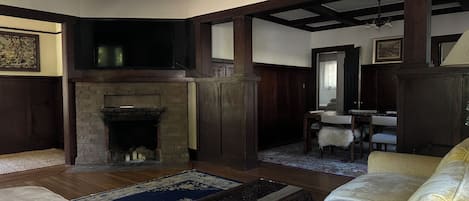 A living room with a fireplace, a chandelier, and a dining area with a table and chairs.