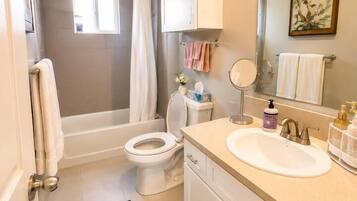 A bathroom with a bathtub, toilet, sink, and a mirror.