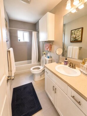 A bathroom with a bathtub, toilet, sink, and a mirror. - Trendy North Park Getaway | W/D + Full Kitchen (San Diego)