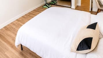 A bedroom with a large bed, a ceiling fan, a mirror, and exercise equipment.