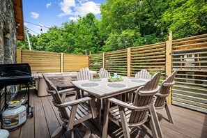 Eine Terrasse im Freien mit Tisch und Stühlen, einem Grill und einem Holzzaun.