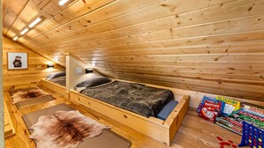 Et interiør af en træhytte med en seng, et spisebord og et billede i ramme på væggen.