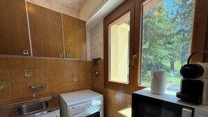Eine Küche mit Einbauofen, Mikrowelle und einem Fenster mit Blick auf Bäume.