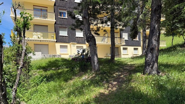 Ein mehrstöckiges Gebäude mit Balkonen, umgeben von Bäumen und Gras.