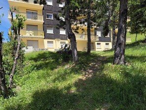Ein mehrstöckiges Gebäude mit Balkonen, umgeben von Bäumen und Gras.