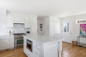Une cuisine moderne avec des meubles blancs, un îlot central et des appareils électroménagers en acier inoxydable.