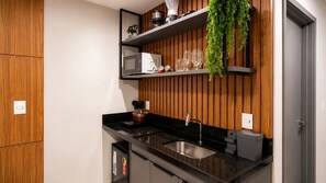 Eine moderne Küche mit schwarzer Arbeitsplatte, Spüle aus Edelstahl, Holzverkleidung an der Wand und einer hängenden Pflanze.