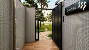 A corridor with tiled walls, a wooden floor, and a gate leading to a beach view. - Beachfront property in Bessa | Ocean view with pool (João Pessoa)