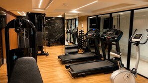 Ein modernes Fitnessstudio mit Laufbändern, einer Gewichtbank und einem Rudergerät.