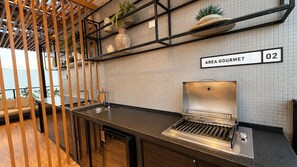 Una kitchenette con una parrilla empotrada, un lavamanos y una estantería con plantas en macetas.