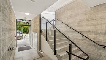 A modern interior with a staircase, a glass door leading outside, and a concrete wall.