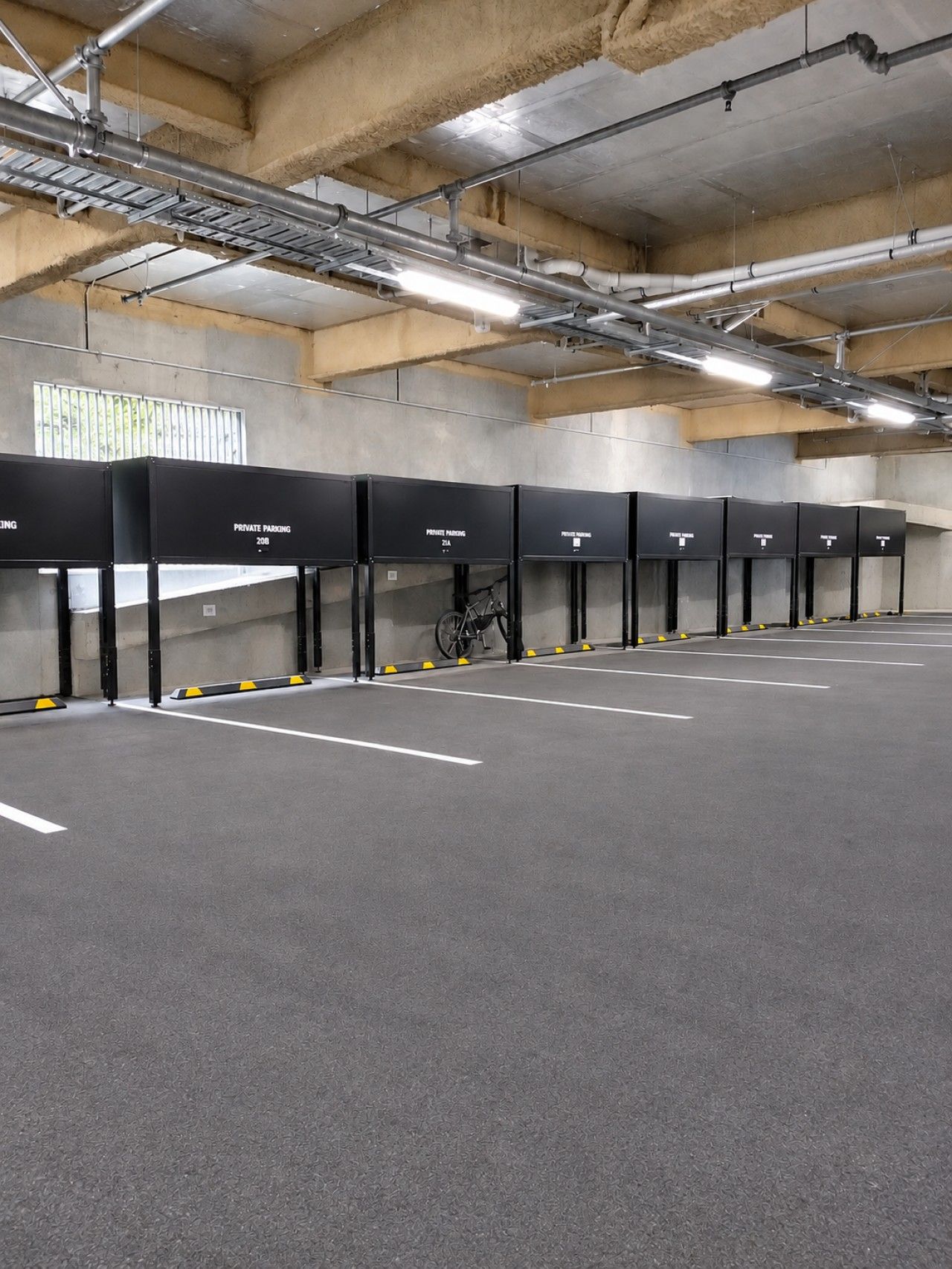 A parking garage with multiple parking bays, some marked as private, and a bicycle parked in one.