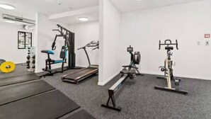 Ett gym med konditionsmaskiner, styrketräningsutrustning och ett löpband.