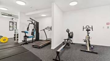 A gym with cardio machines, weightlifting equipment, and a treadmill.
