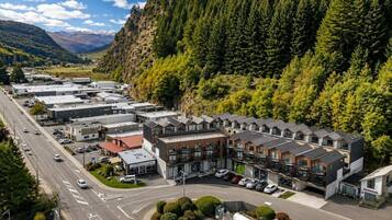 A modern hotel with a row of rooms, a parking lot, and a road with vehicles.