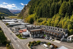 Ein modernes Hotel mit mehreren Zimmern, einem Parkplatz und einer Straße mit Fahrzeugen.
