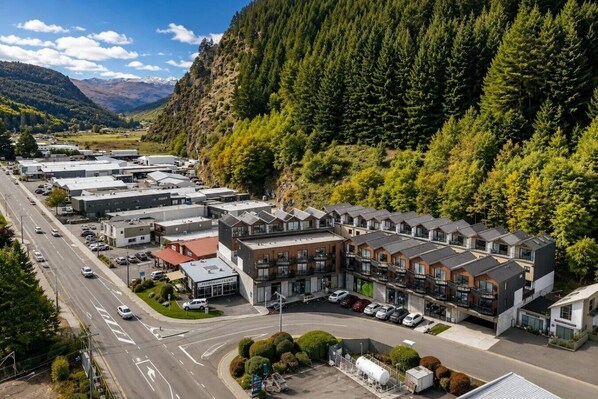 Un hotel moderno con varias habitaciones, un estacionamiento y una carretera con vehículos.