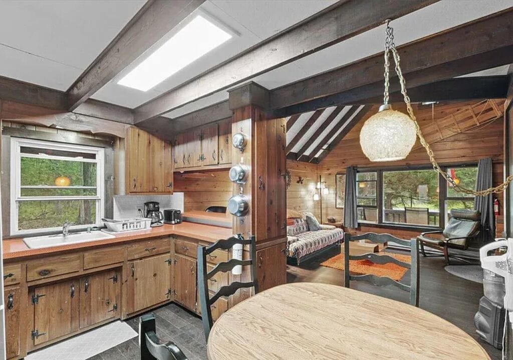 L’intérieur d’un chalet rustique comprend une cuisine, un coin repas et un lit offrant une vue agréable.