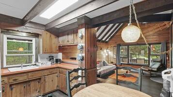 L’intérieur d’un chalet rustique comprend une cuisine, un coin repas et un lit offrant une vue agréable.