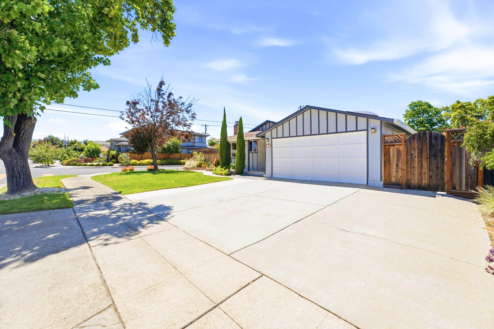 A residential driveway leading to a garage with a wooden fence and a tree.