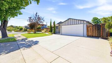 A residential driveway leading to a garage with a wooden fence and a tree.