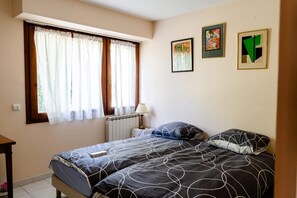 A bedroom with two beds, a radiator, a lamp, and three framed artworks on the wall. - L'Orée du Bois - SAUGNAC ET CAMBRAN (SAUGNAC ET CAMBRAN)