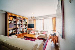 A living room with a sofa, armchairs, a coffee table, a bookshelf, a TV, and a painting on the wall. - L'Orée du Bois - SAUGNAC ET CAMBRAN (SAUGNAC ET CAMBRAN)