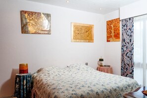 Een slaapkamer met een bed, nachtkastje, lamp en drie decoratieve wandpanelen.