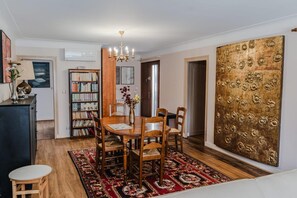 A dining area with a wooden table, chairs, a chandelier, a bookshelf, and a large decorative panel. - L'Orée du Bois - SAUGNAC ET CAMBRAN (SAUGNAC ET CAMBRAN)