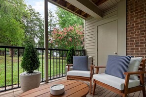 A covered patio with two wooden chairs, a round wooden table, and a potted plant. - Bright & Relaxing 2BR near Ballantyne (Charlotte)