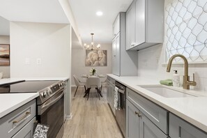 A modern kitchen with a built-in oven, a dining area with a round table, and a patterned backsplash. - Bright & Relaxing 2BR near Ballantyne (Charlotte)
